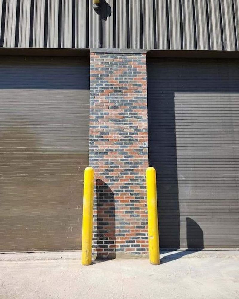 A brick wall with two yellow poles in front of it