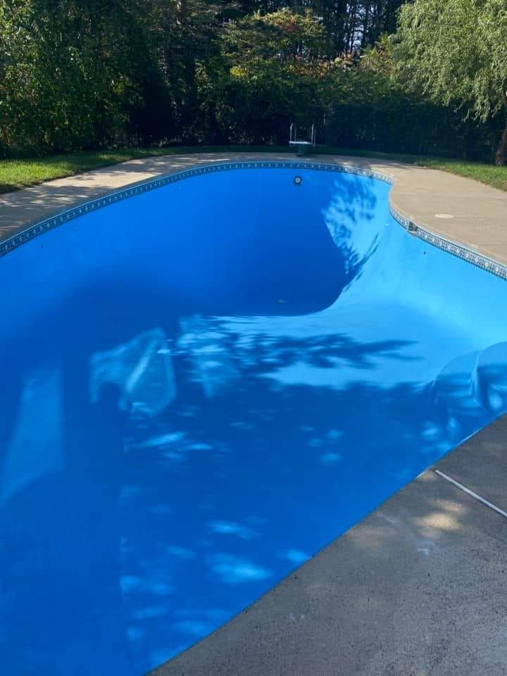 A large blue swimming pool with trees in the background.
