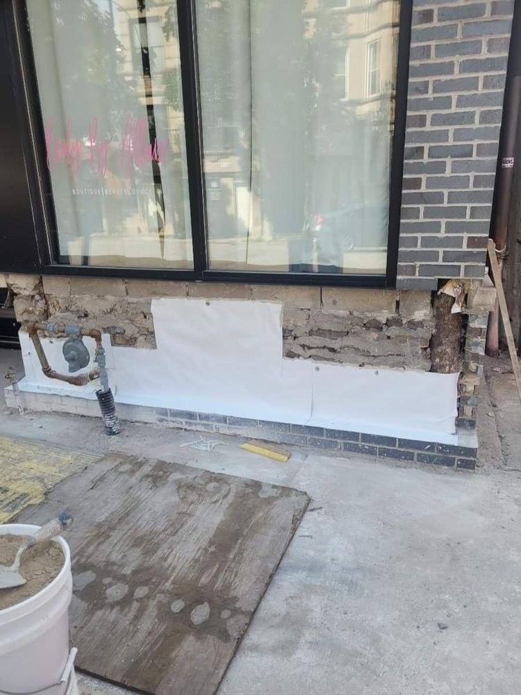A brick wall is being remodeled with a white sheet of paper on it.