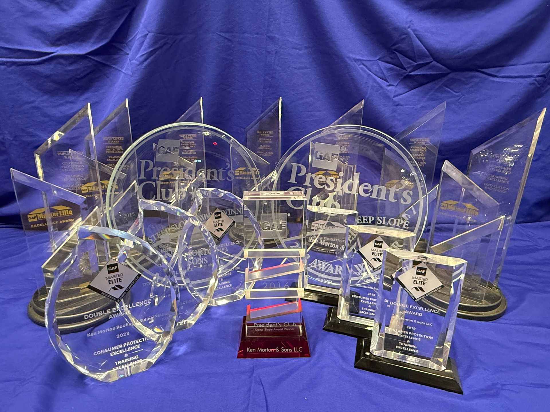 A collection of glass awards on a blue tablecloth, including 