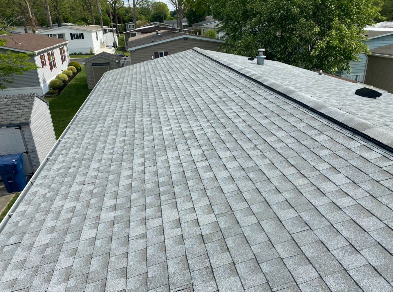Gray shingled roof with a black strip along the top, viewed from above on a sunny day.