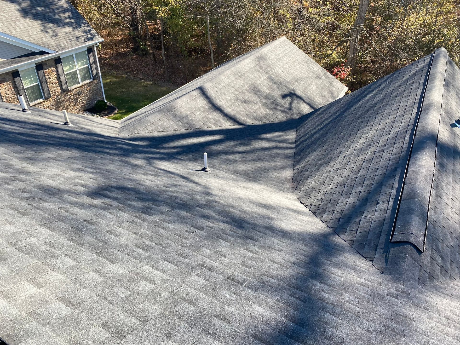 Gray shingle roof with multiple angles under sunlight.
