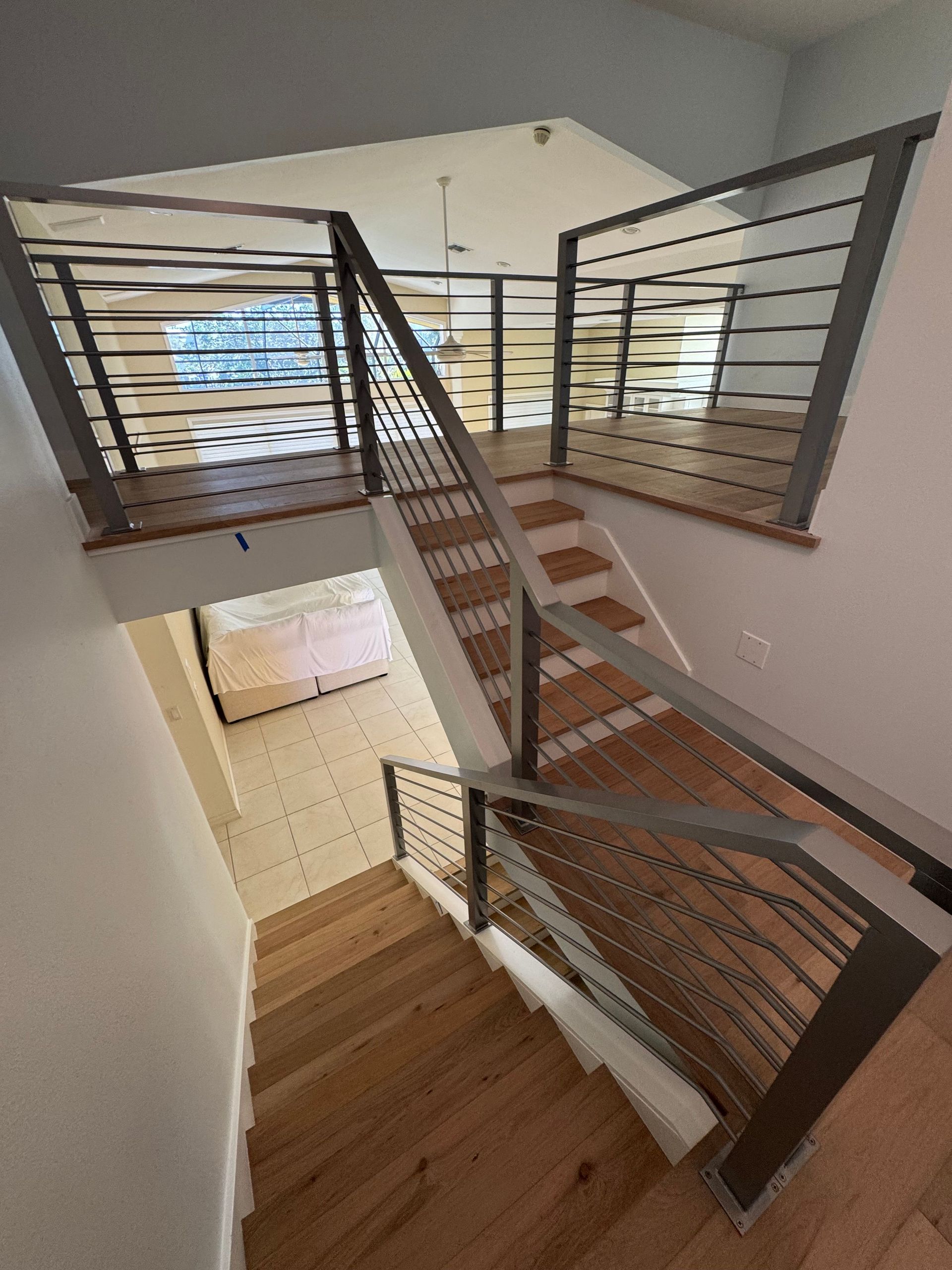 Indoor staircase with wood steps, metal railings, and a view to a bright lower level.