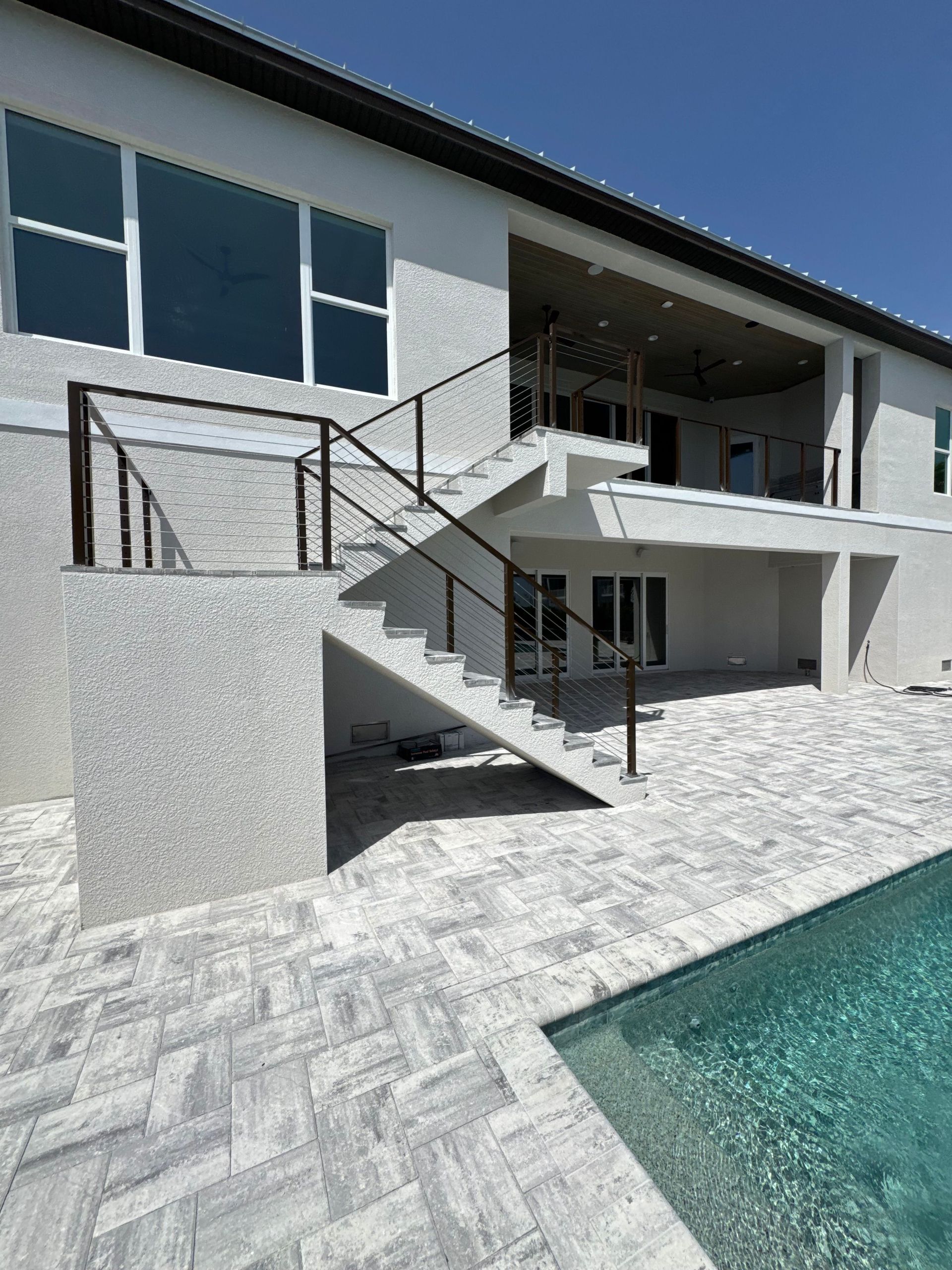 Modern house patio with outdoor stairs beside a swimming pool.