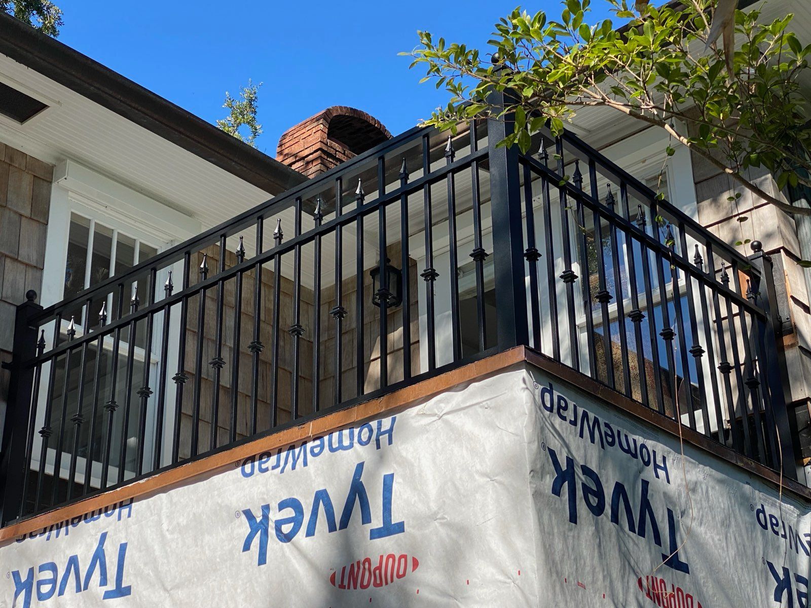 Black metal balcony with white railings and blue Twix and Whatchamacallit banners on a house.