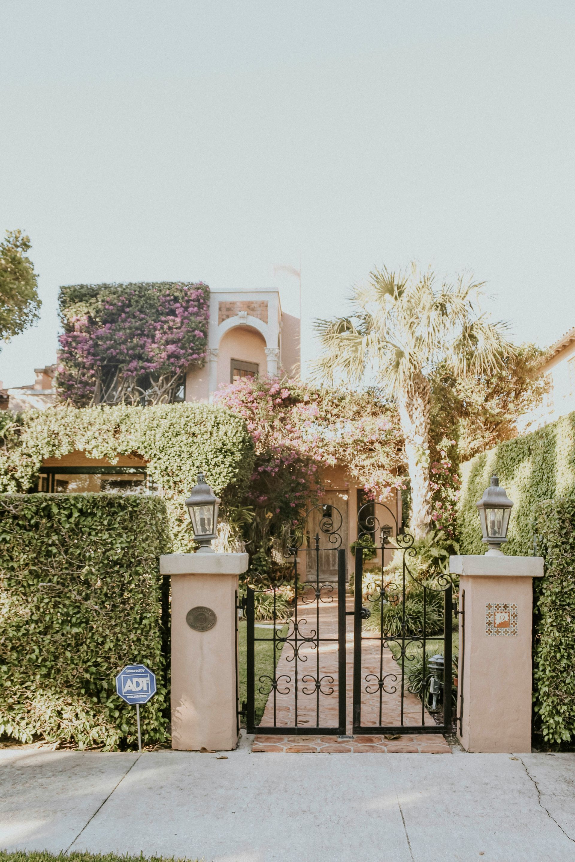 Gated front yard with ivy-covered walls and a small stucco house behind it.