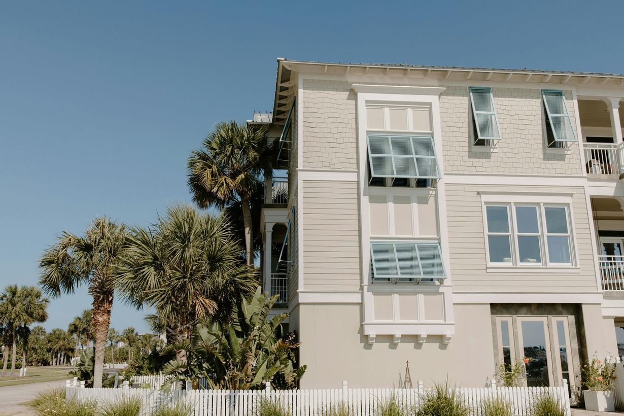Coastal apartment building with palm trees under a clear blue sky.