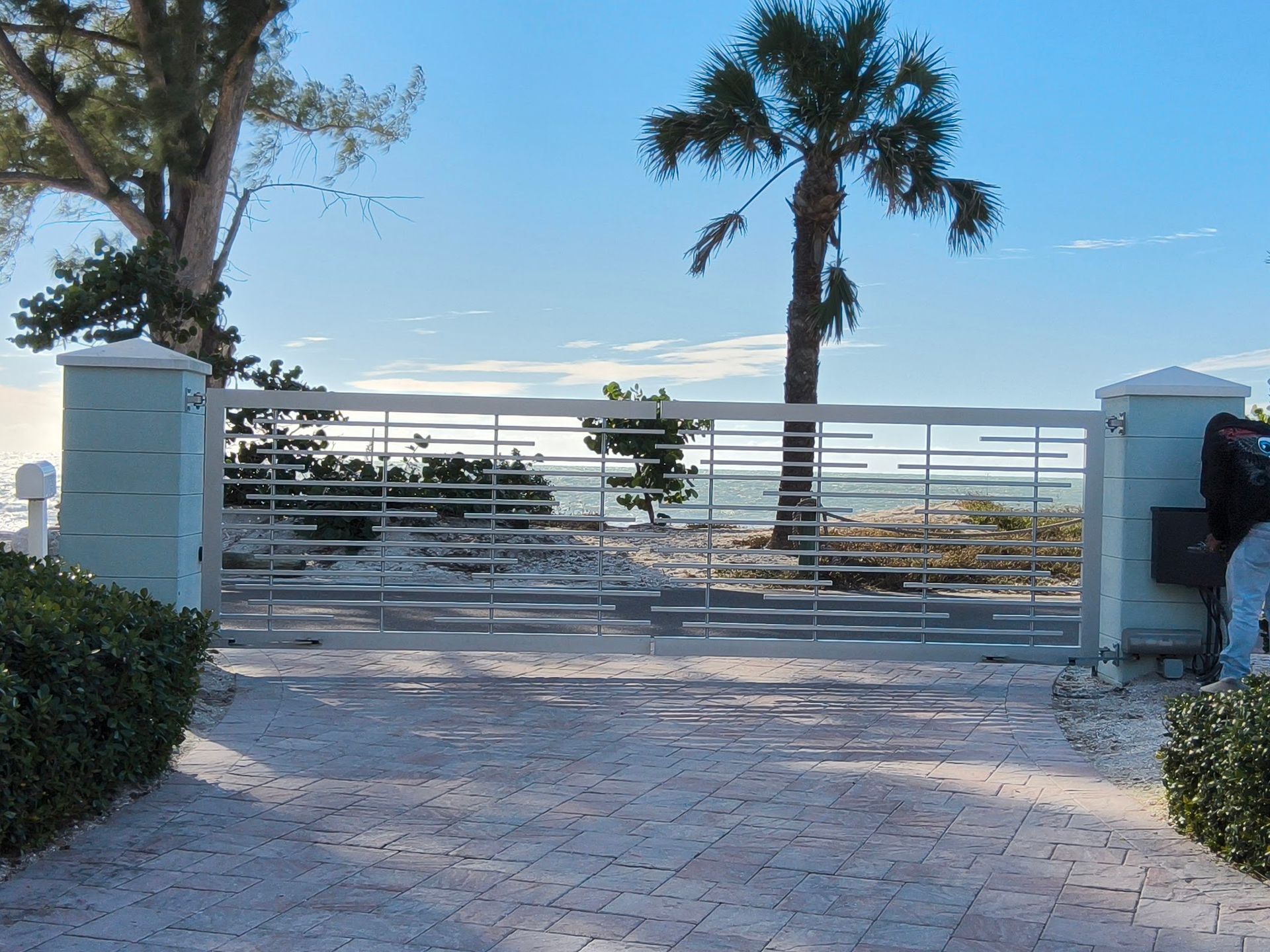 Gate to beach with palm tree and blue sky.