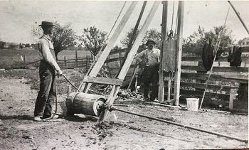 A black and white photo of two men working on a machine.