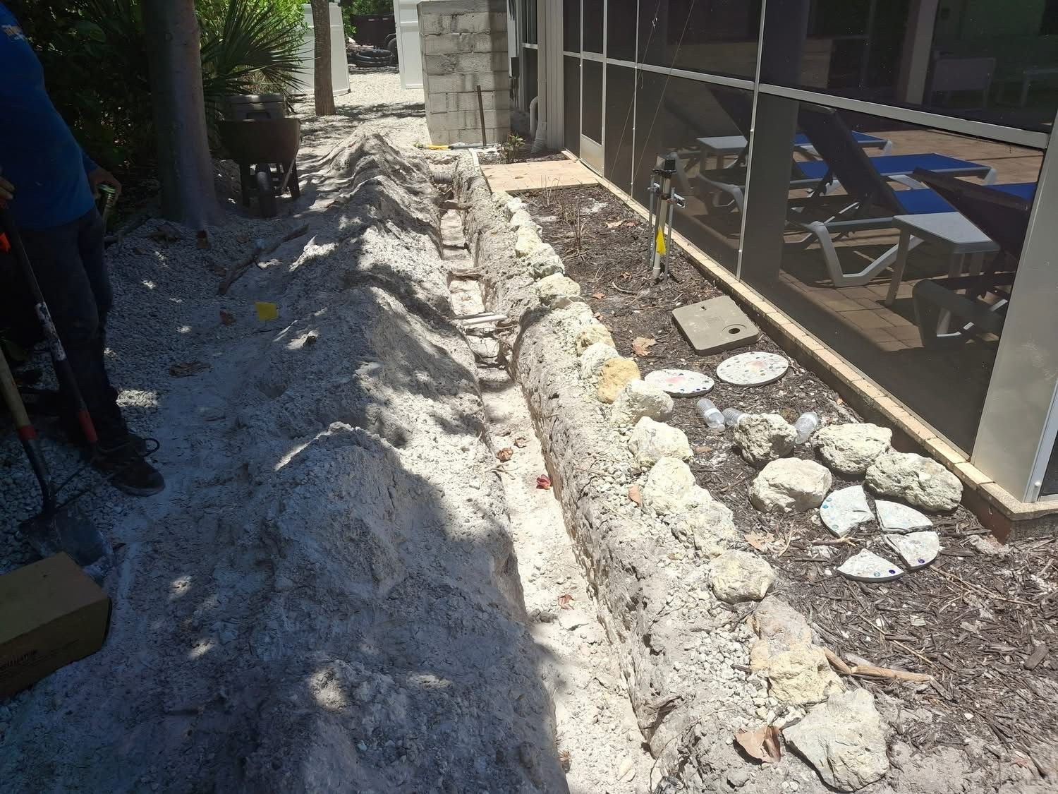 A man is digging a hole in the ground in front of a screened in porch.