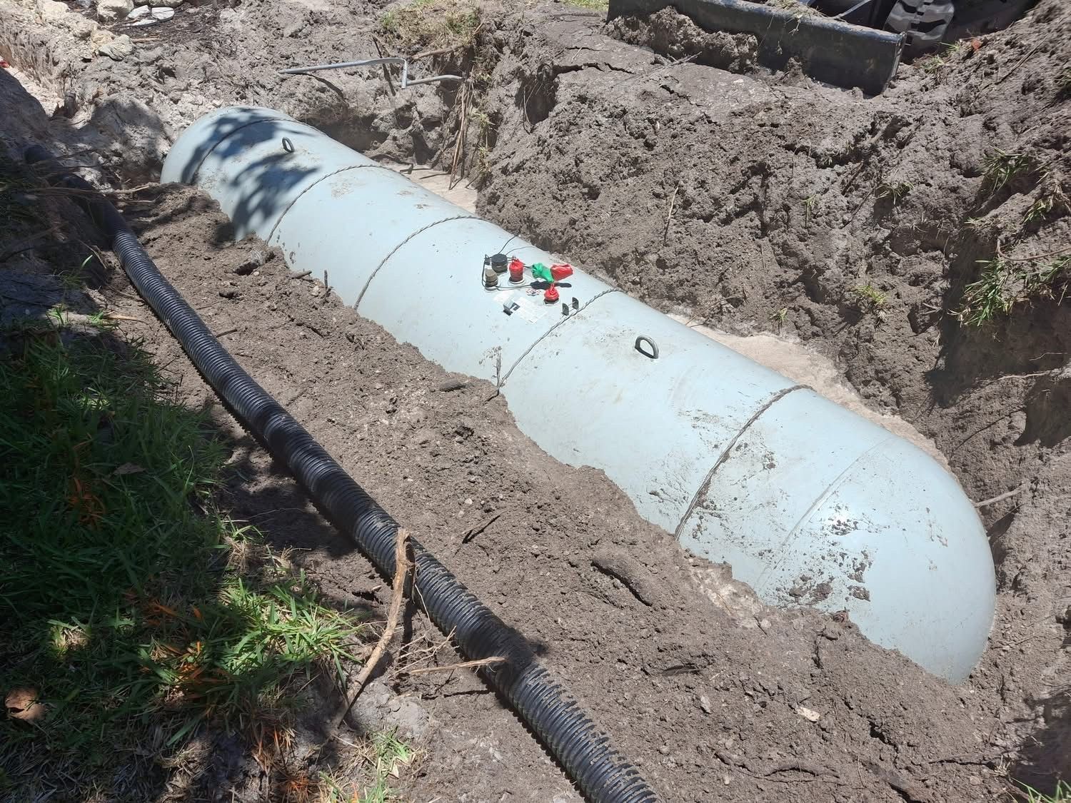 A large white pipe is laying in the dirt.