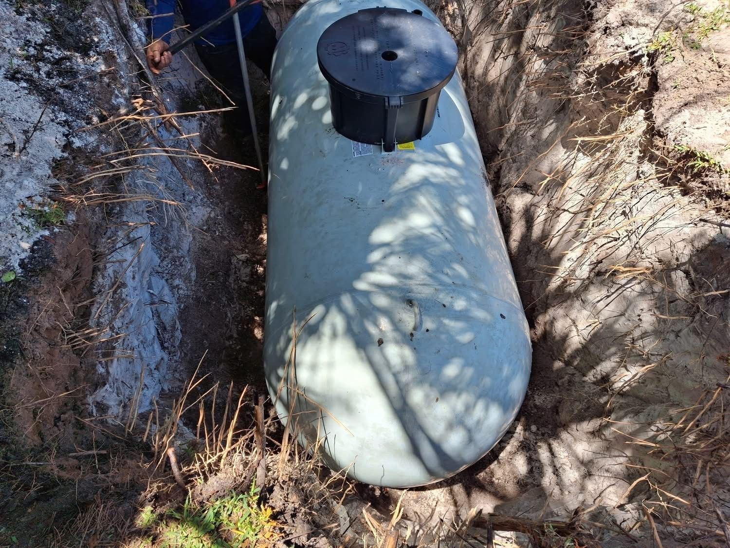 A man is standing next to a large tank in the dirt.