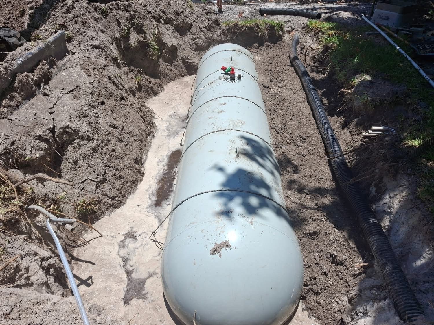 A large white cylinder is sitting in the dirt.