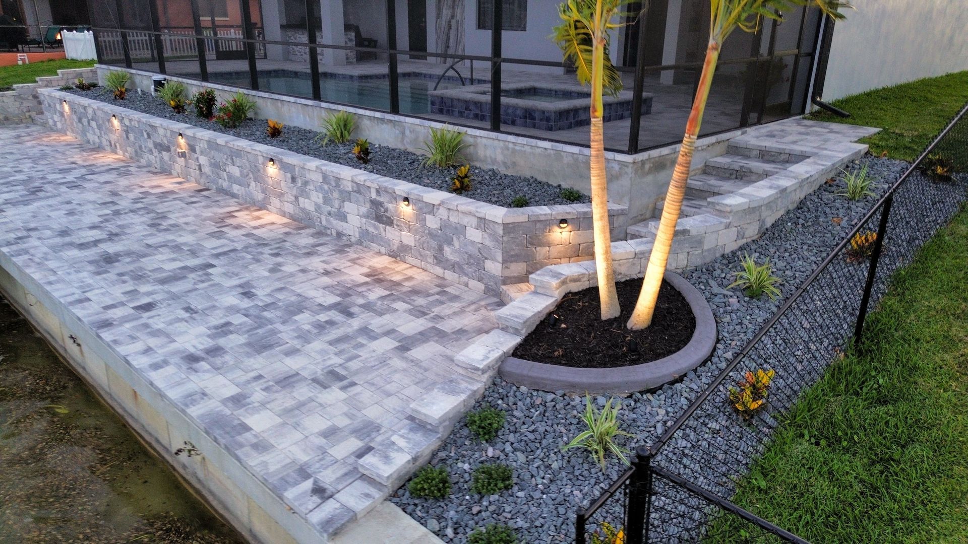 A patio with a tree in the middle of it and a pool in the background.