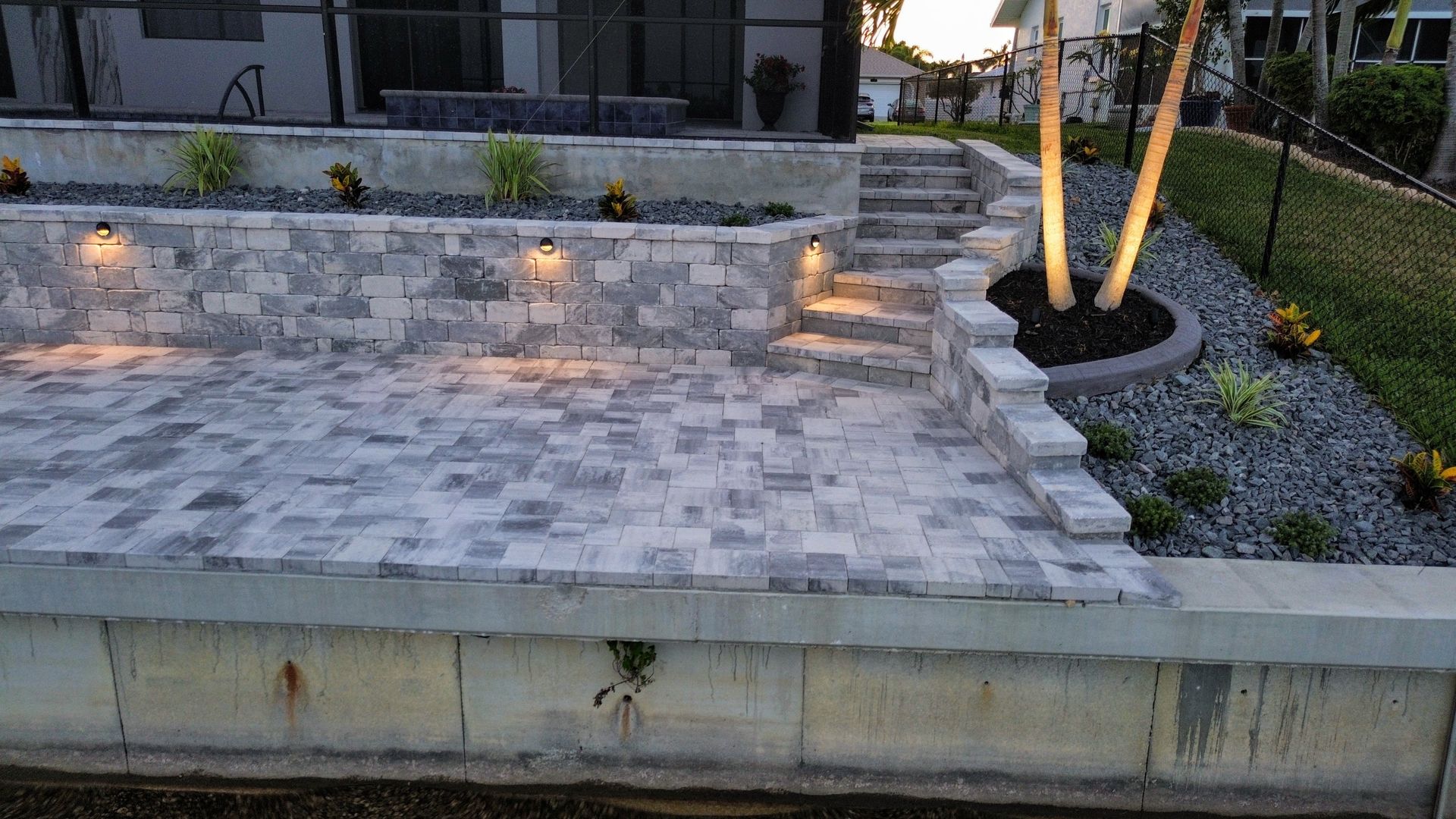 A brick patio with stairs leading up to it is lit up at night.