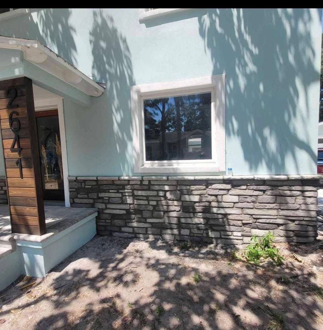 A blue house with a stone wall and a window