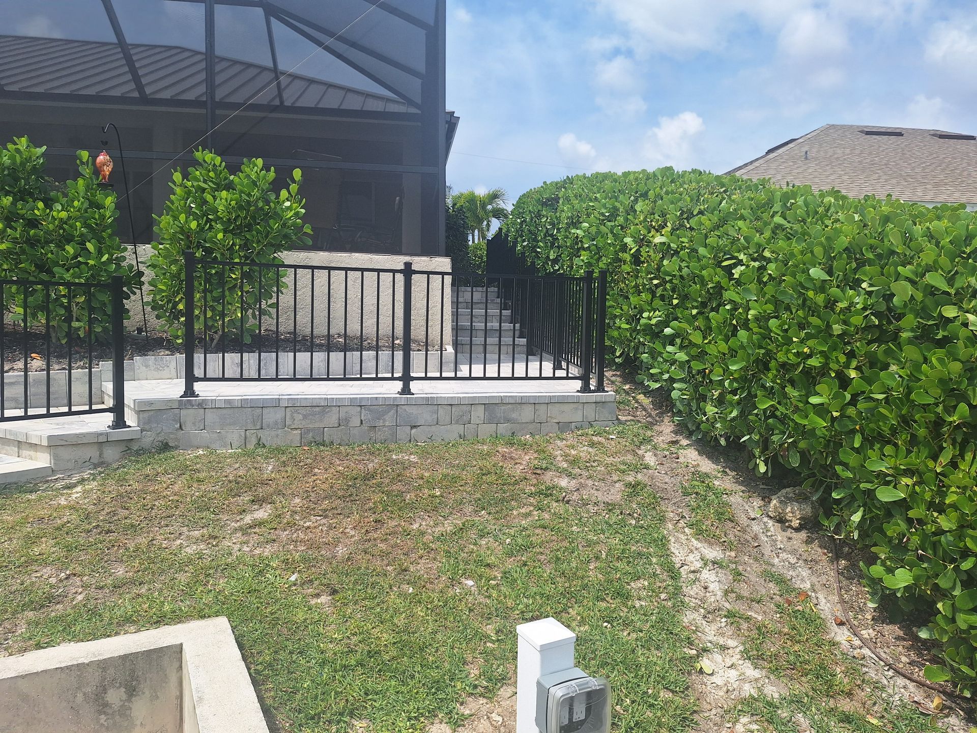 A backyard with a fence and a pool in the background.