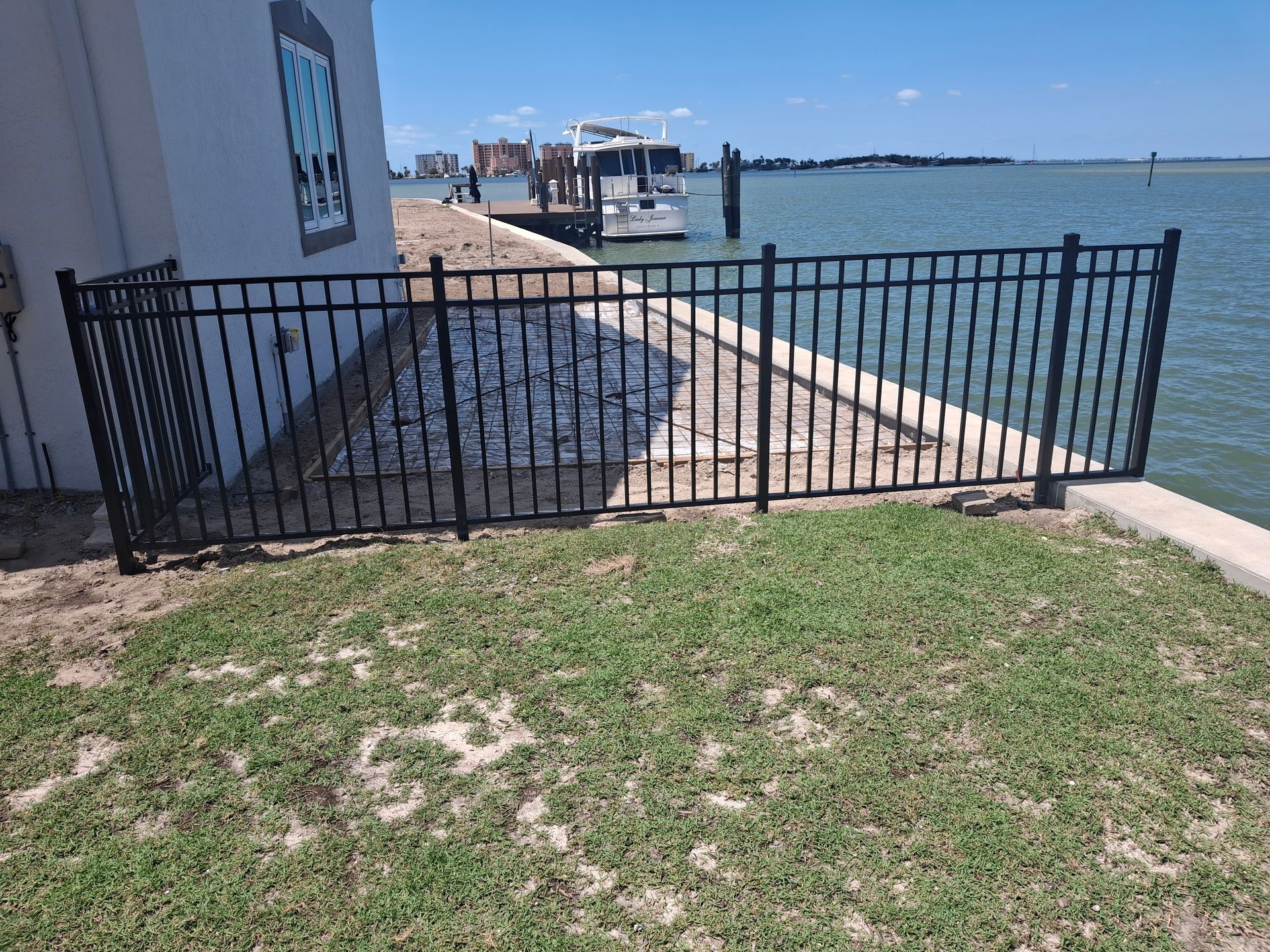 A black fence surrounds a dock next to a body of water.