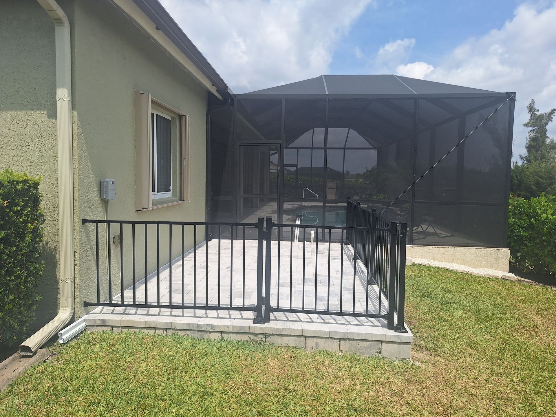 A house with a screened in porch and a fence around it.