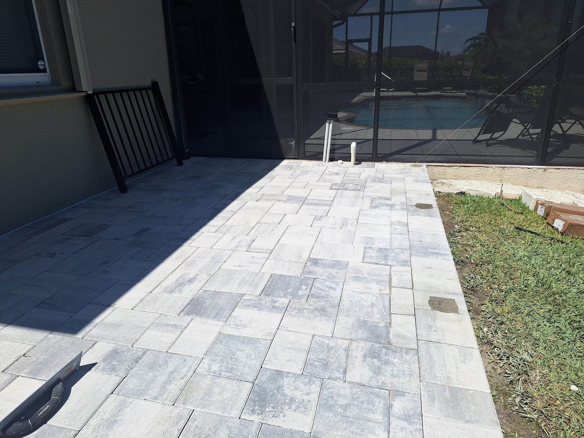 A patio with a fence and a pool in the background.
