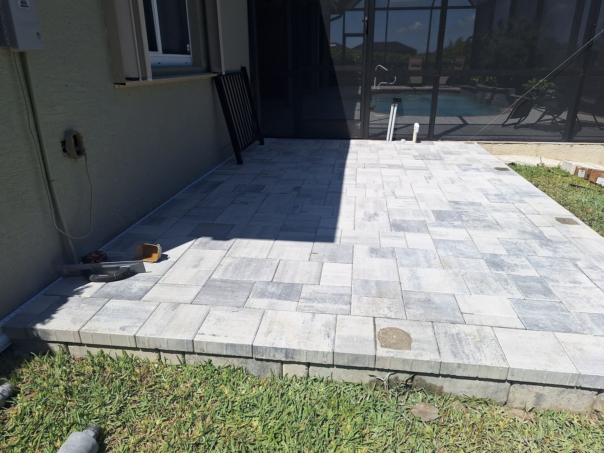 A dog is sitting on a patio next to a house.