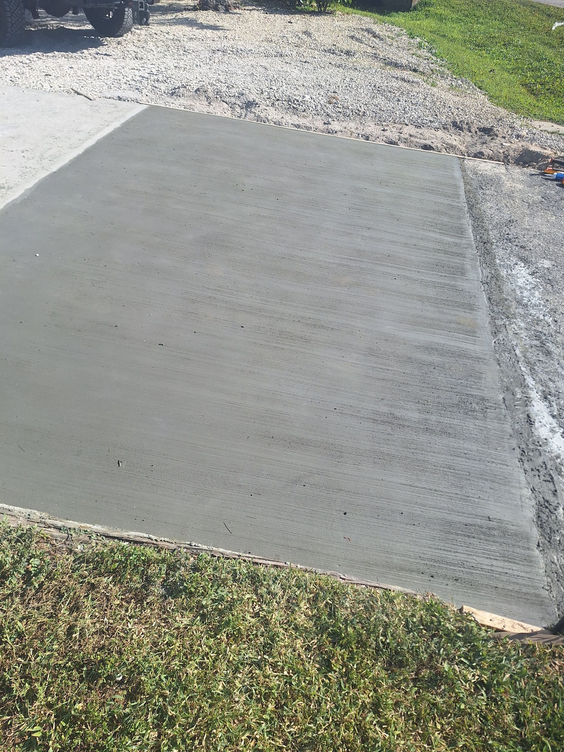 A concrete driveway is being built next to a grassy area.