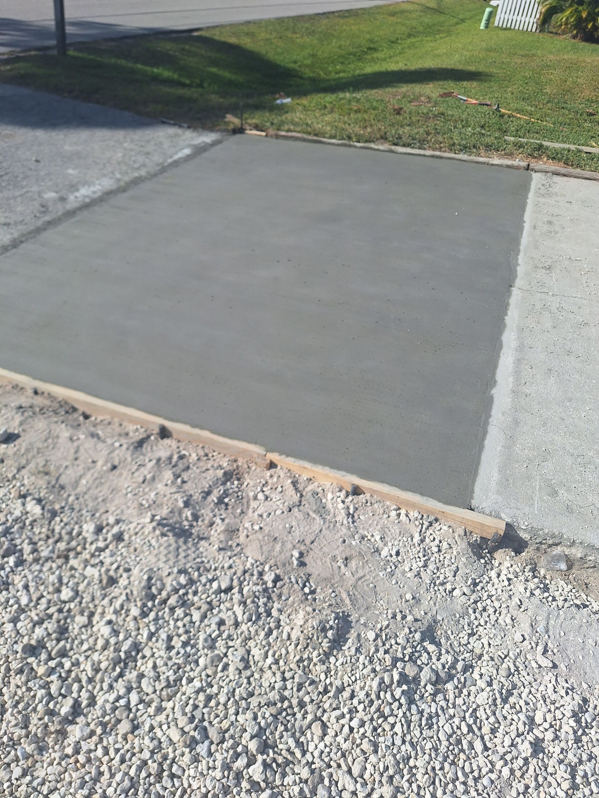 A concrete driveway is being built next to a gravel driveway.