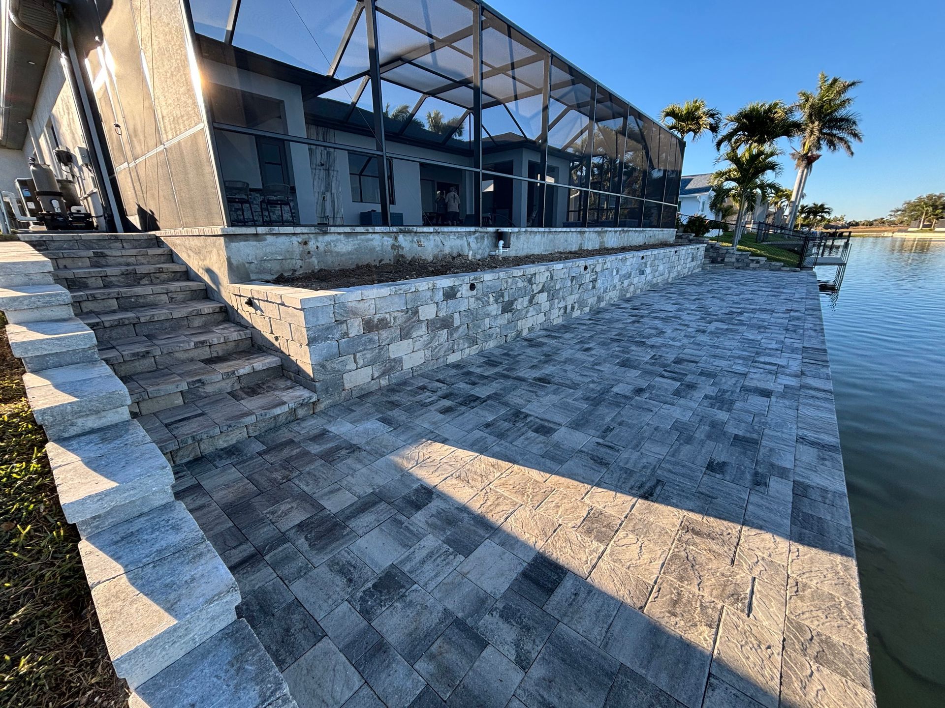 A patio with stairs leading up to a house next to a body of water.