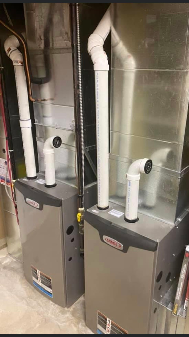 two Lennox furnaces with white exhaust pipes, in a basement
