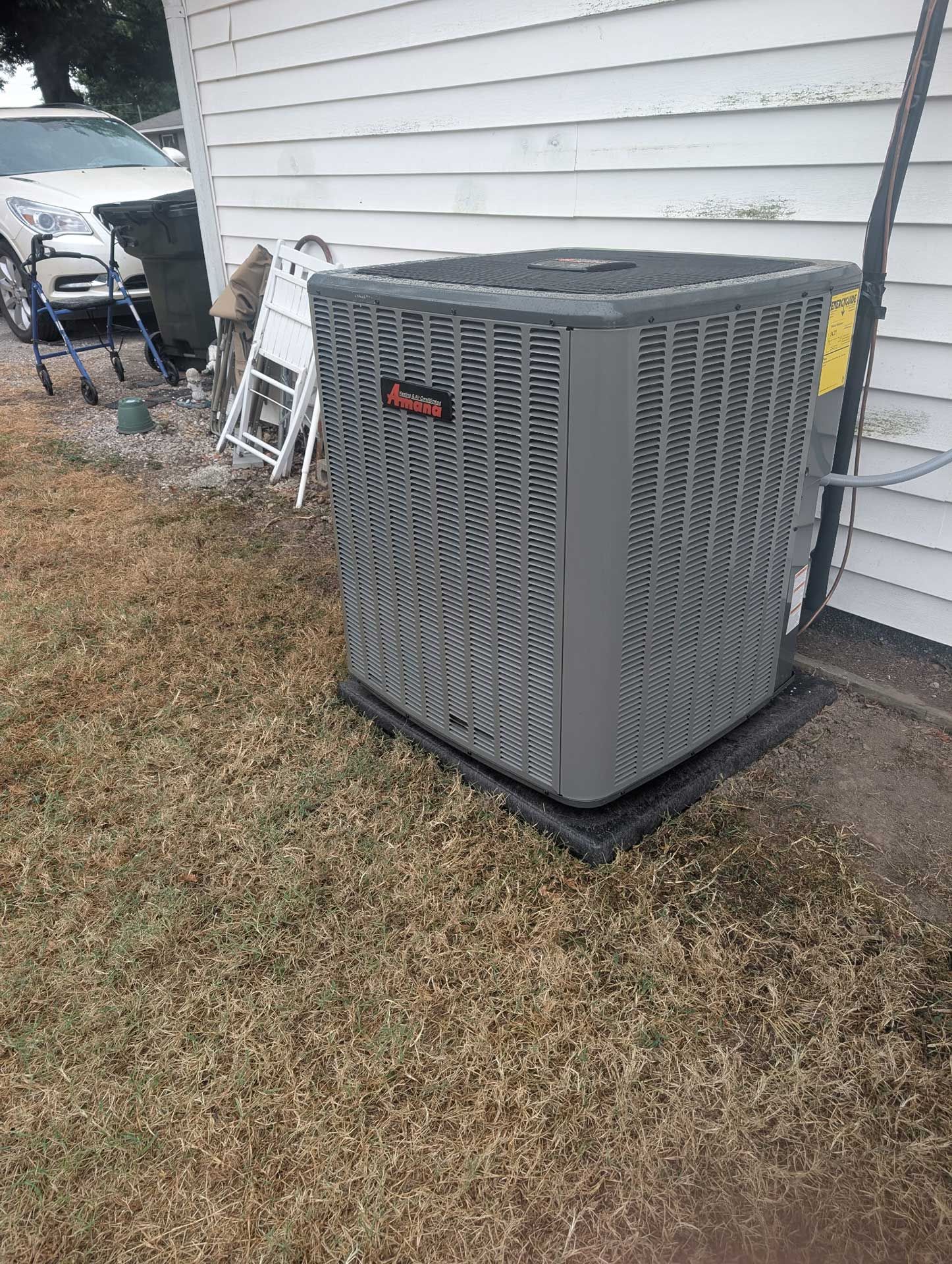 gray air conditioning unit outside a white house on dry grass