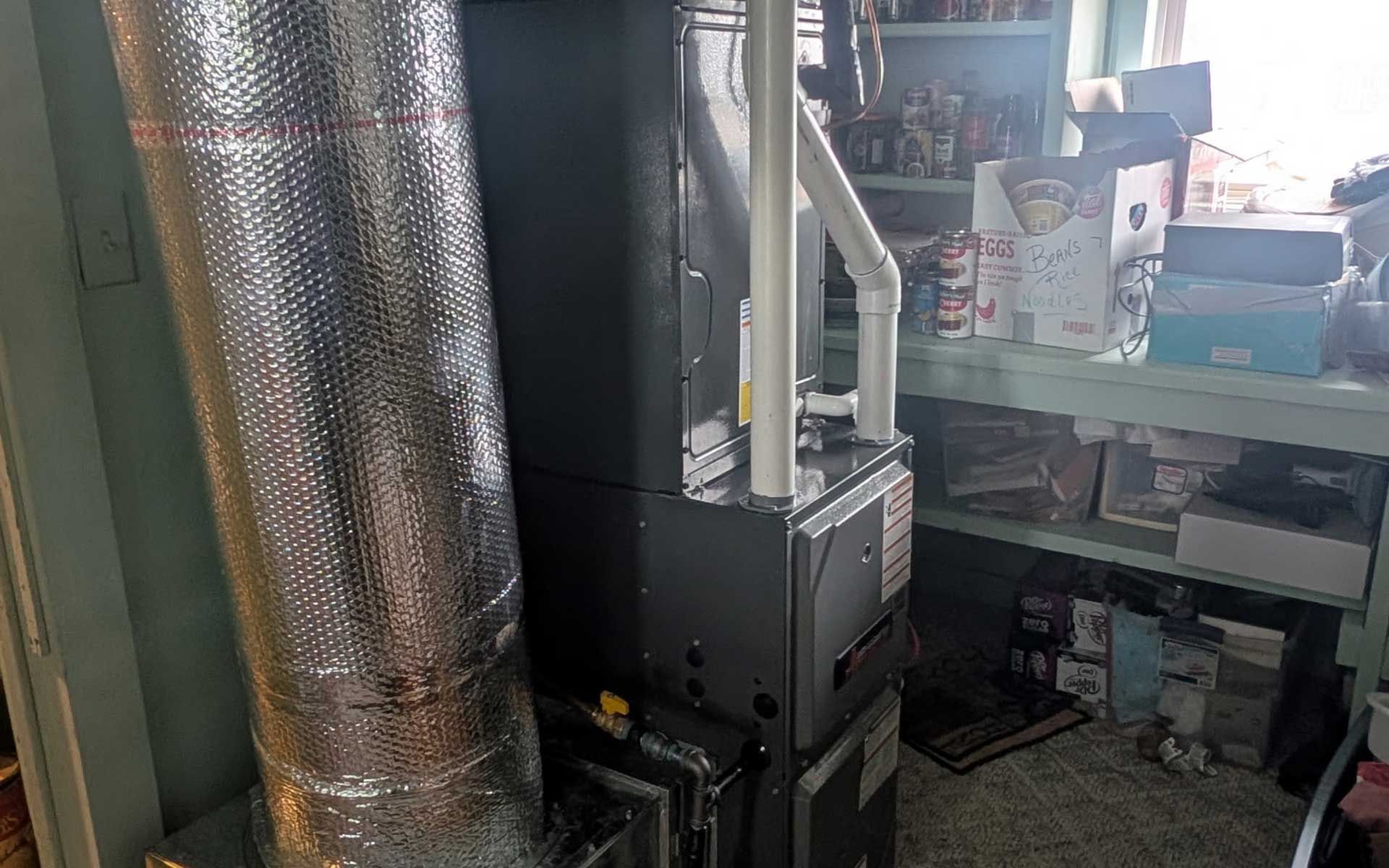 Three large, gray water heaters in a utility room with HVAC equipment and piping.