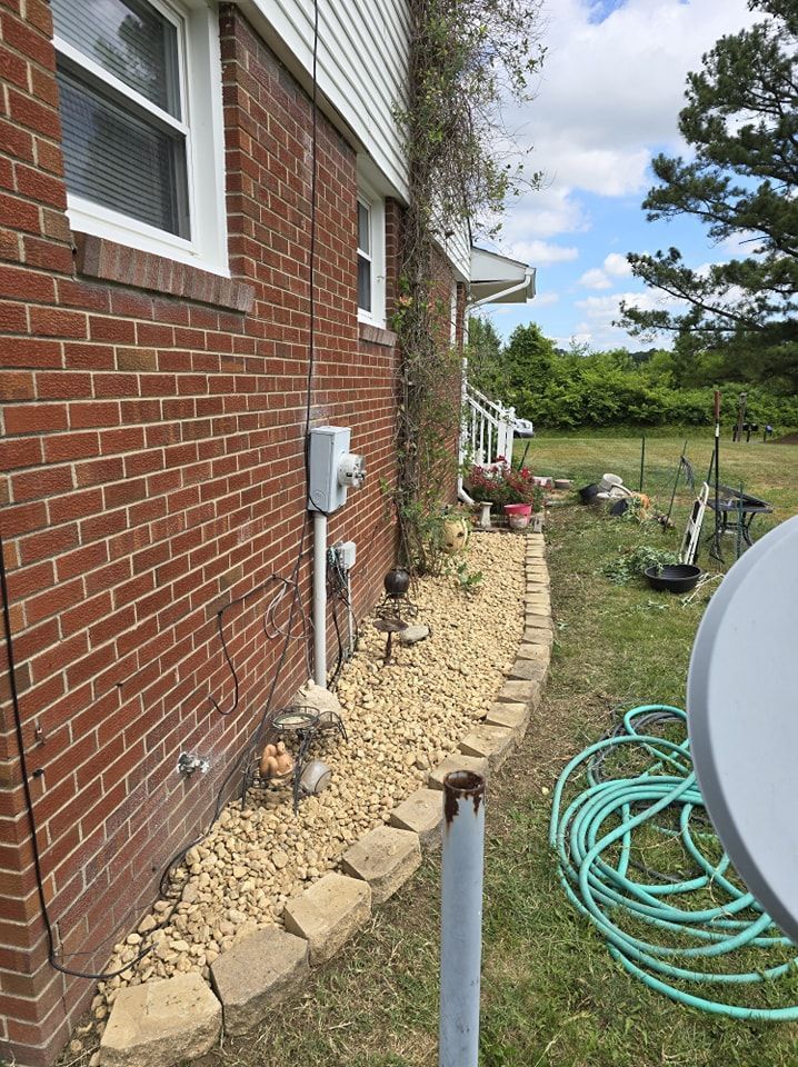 A brick house with a hose and a satellite dish in front of it.