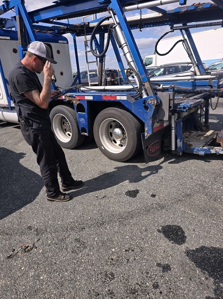A man is standing in front of a truck talking on a cell phone.