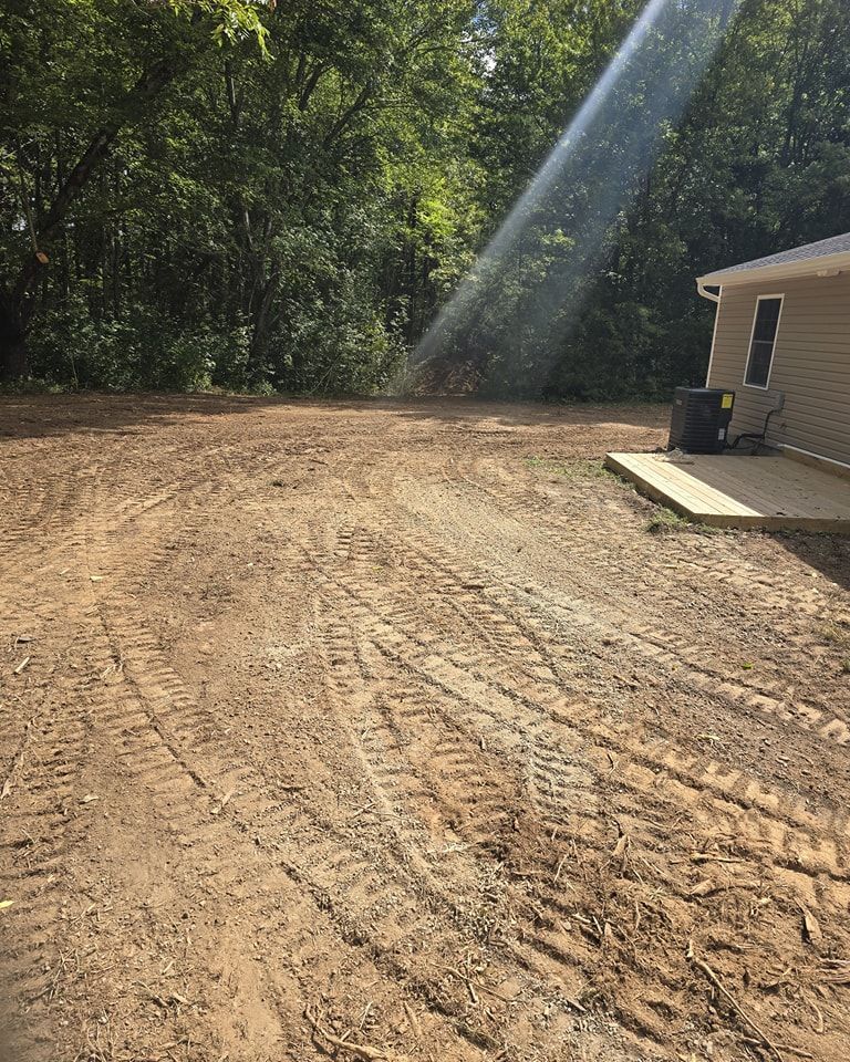 A dirt road leading to a house with trees in the background.