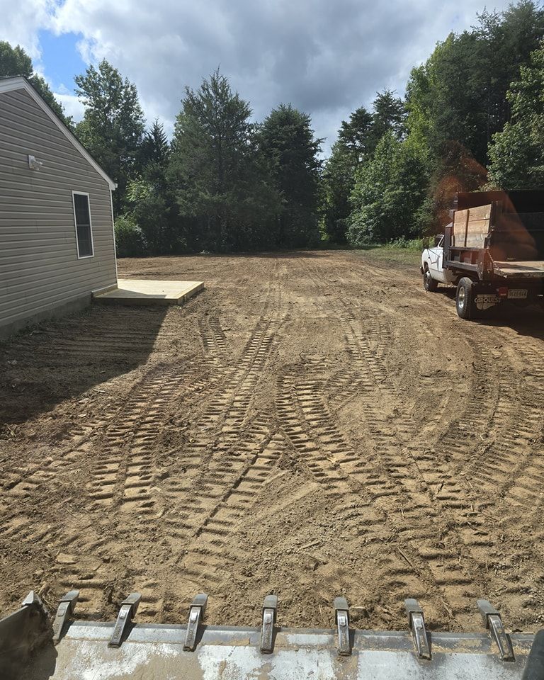 A white truck is parked in the dirt in front of a house