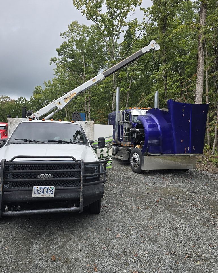A white truck is parked next to a blue truck with a crane attached to it.