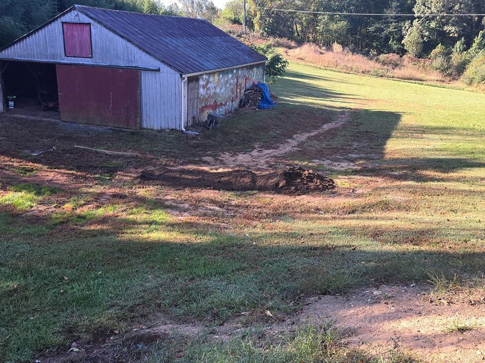A barn is sitting in the middle of a grassy field.
