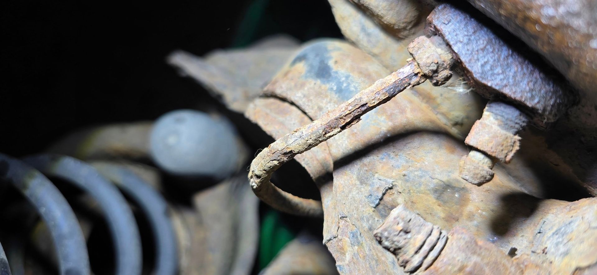 Close-up of a rusty metal automotive part with bolts and coiled springs