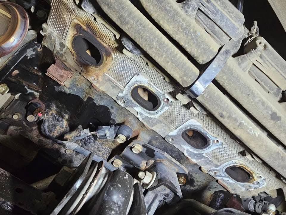 Close-up of a damaged car engine undercarriage with rusted metal parts and exposed components.