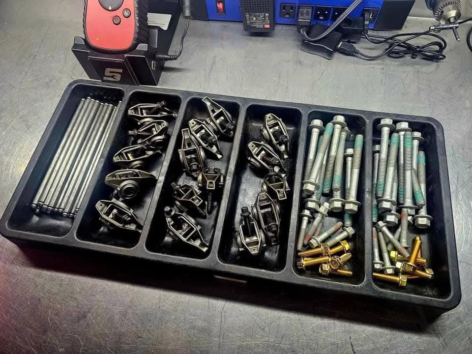 Organized tray of assorted bolts, screws, and fasteners on a workbench.