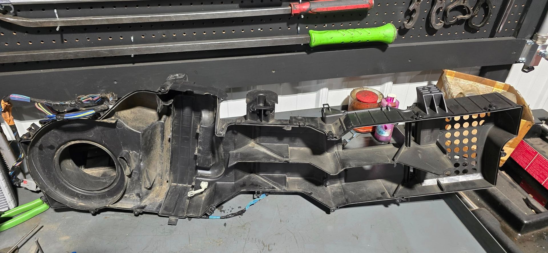 Disassembled black mechanical device with cables and tools on a workbench