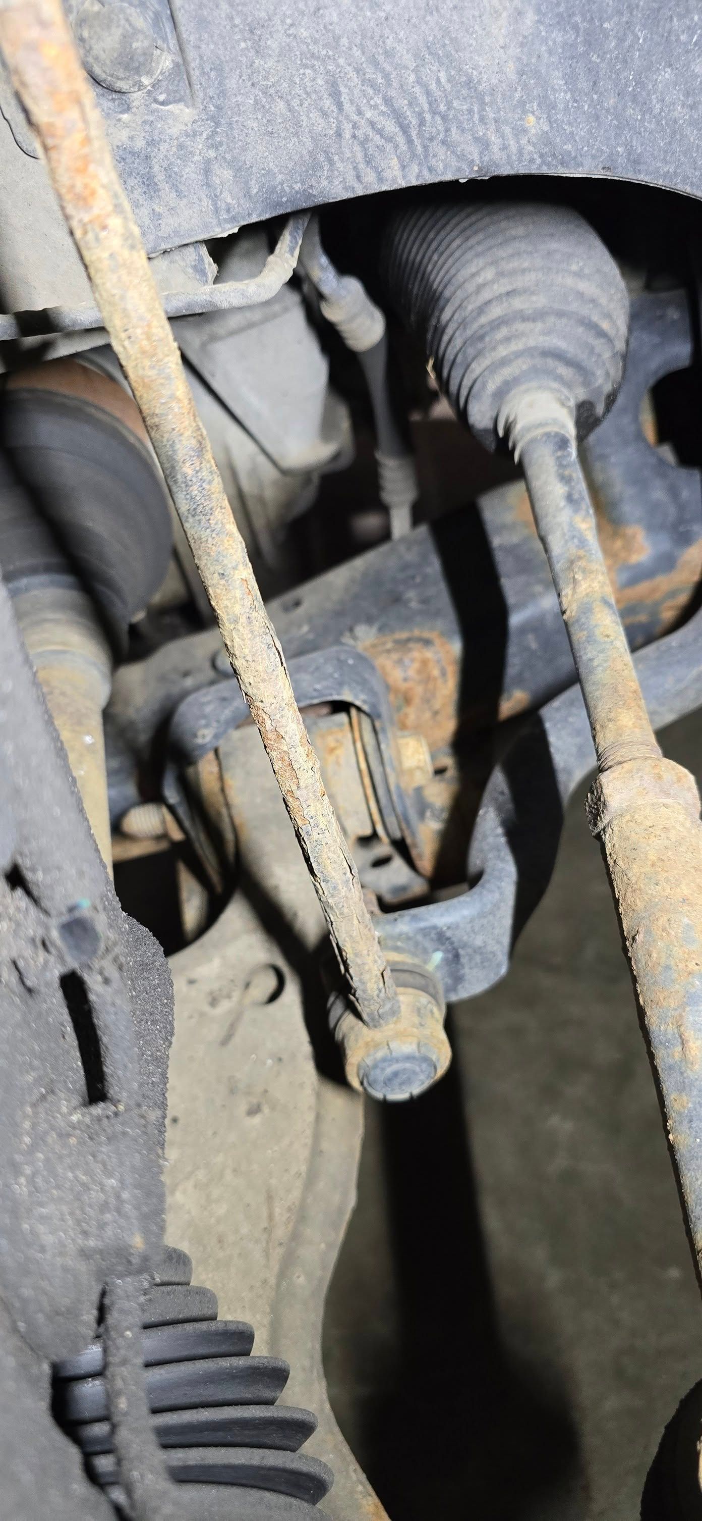 Close-up of a rusty vehicle steering/suspension joint under the wheel well