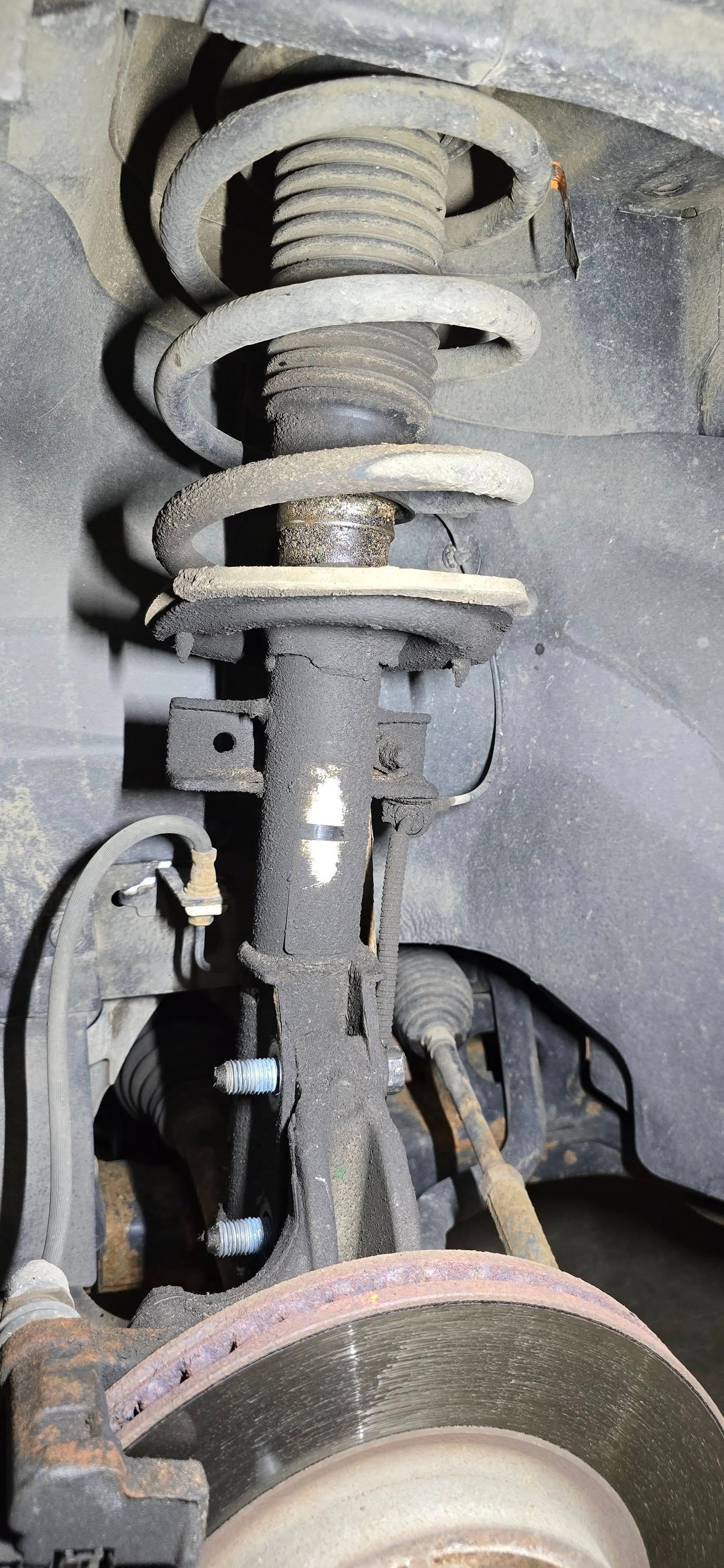 Close-up of a car suspension strut and coil spring inside a wheel well.