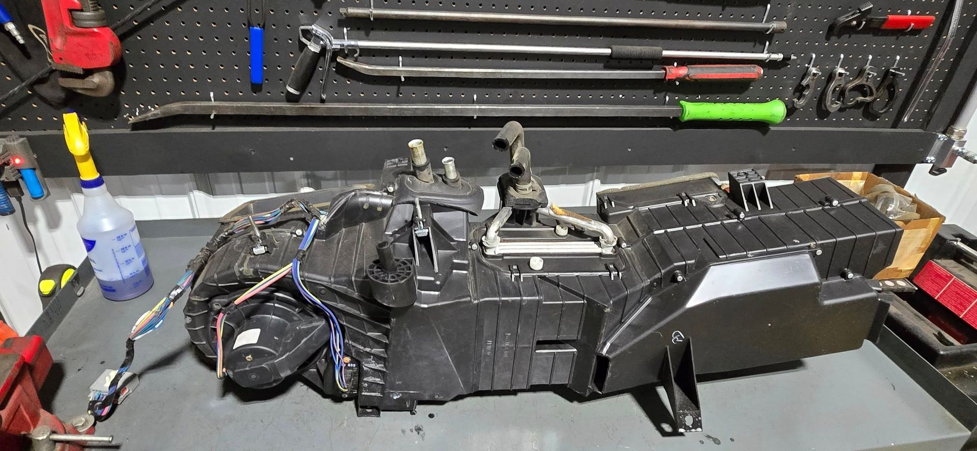 Disassembled black RC car on a workbench with tools and parts in the background