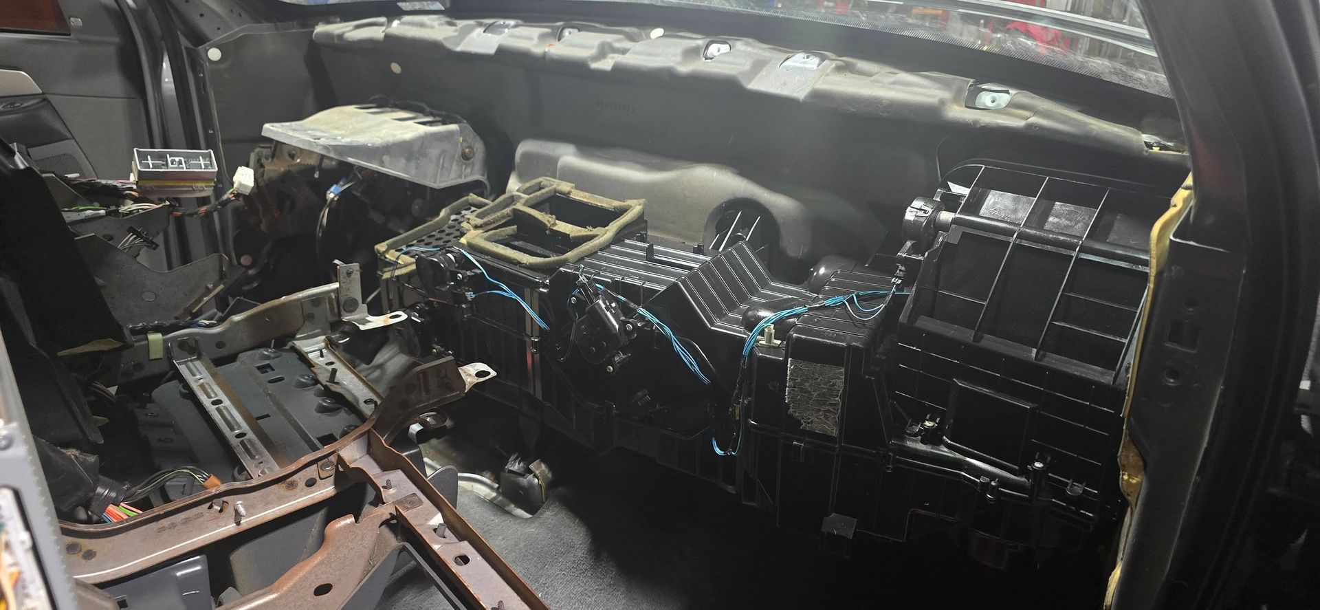 Car engine bay with exposed components and wiring, viewed from above under the hood.