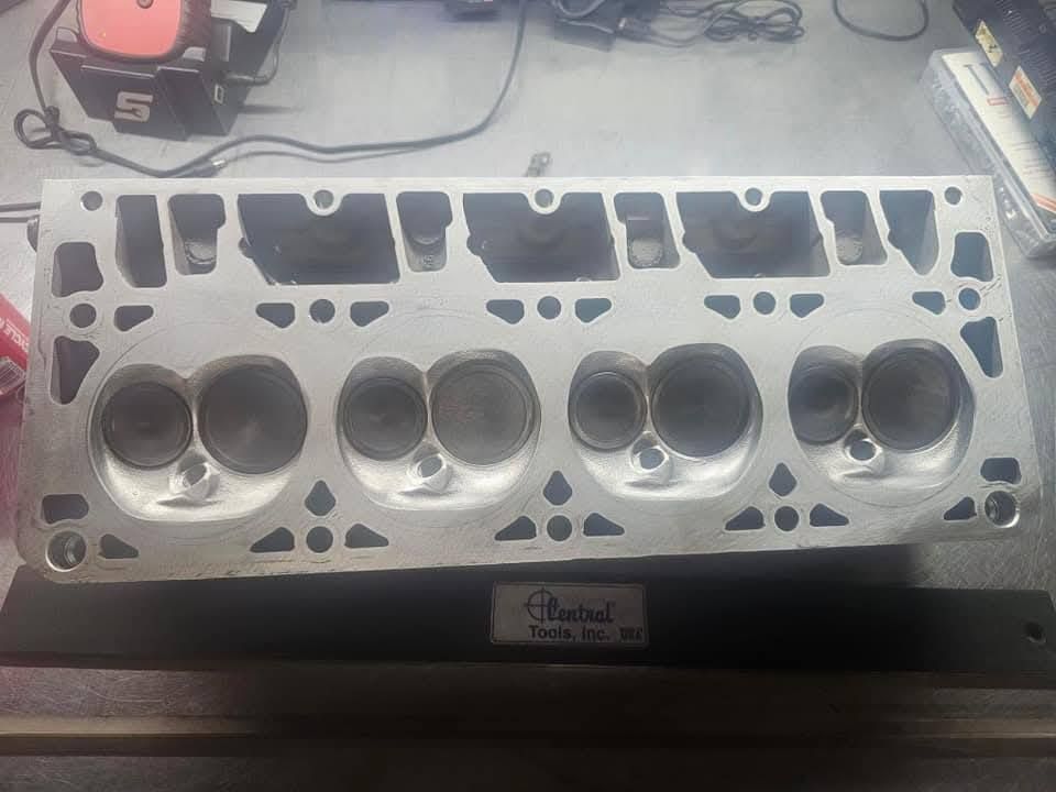 Car engine cylinder head gasket surface with valve and combustion chamber openings on a workbench