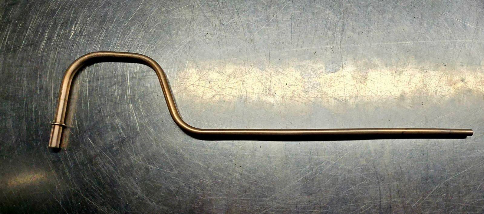 Bent metal rod tool with a hooked end on a dark surface