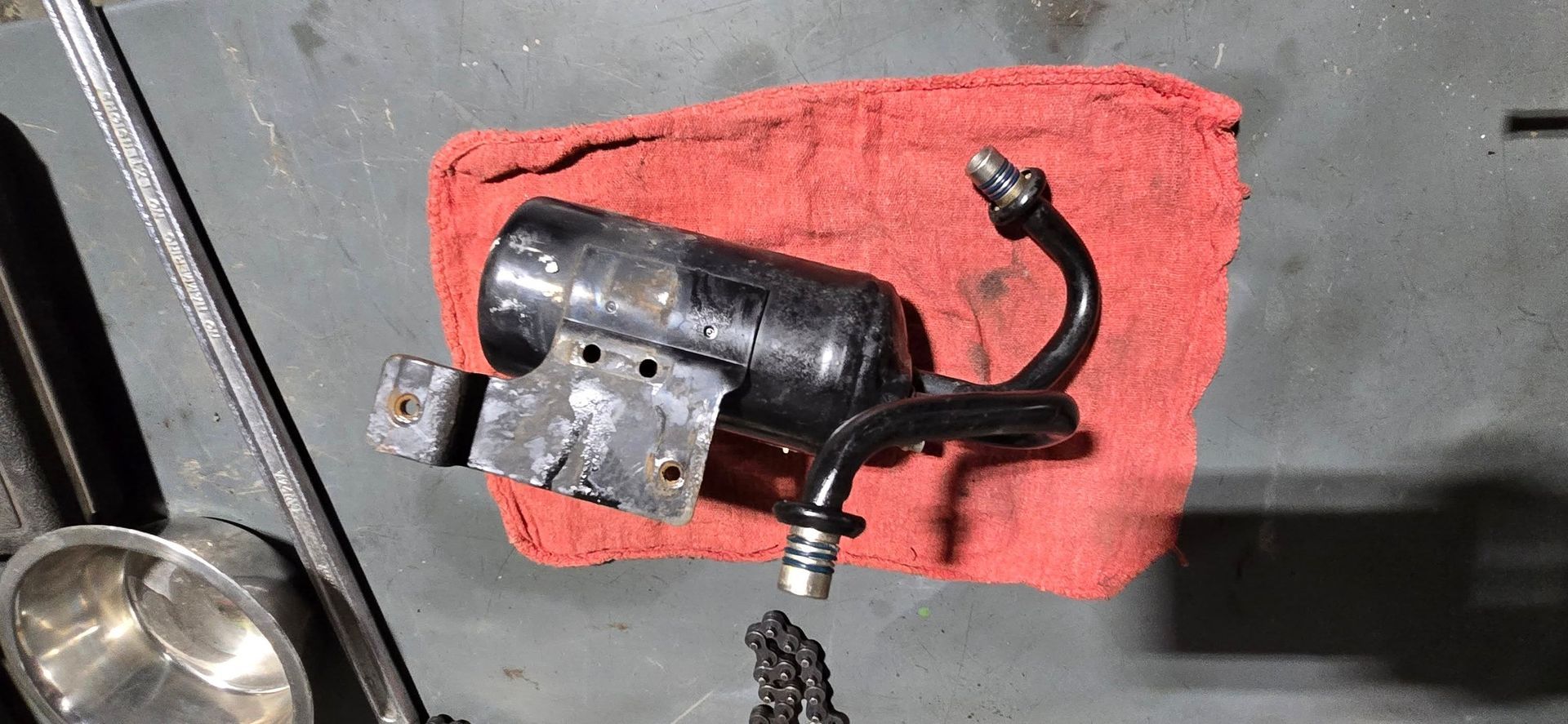 Black cylindrical tool or camera mounted on a bracket over a red cloth on a gray surface
