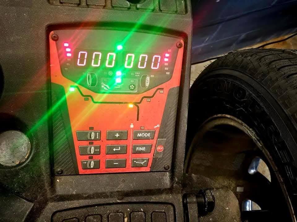 Orange-lit digital control panel with glowing display and buttons beside a large tire