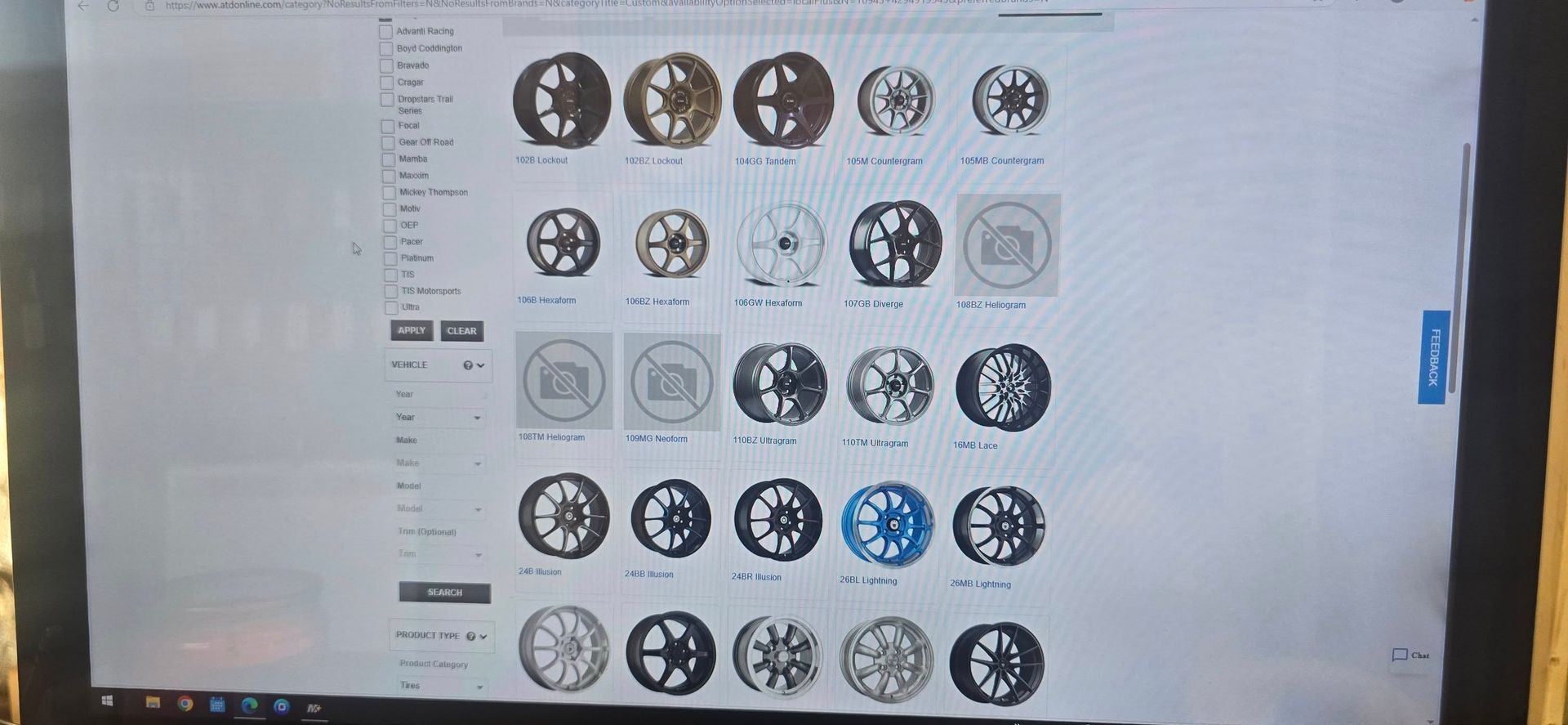 A computer monitor shows a webpage with a grid of circular logo or badge designs in black, gray, and blue.